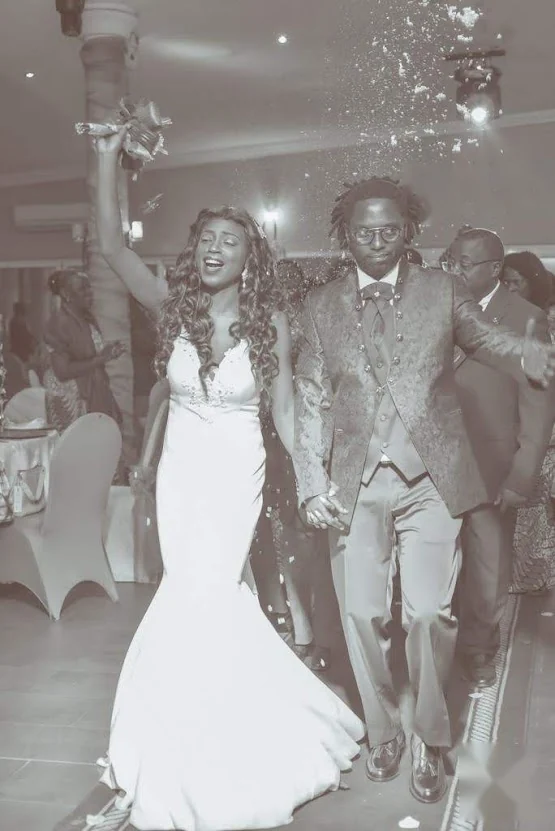 Les mariés entrent dans la salle de réception, la mariée le bouquet levé, sous une pluie de confettis