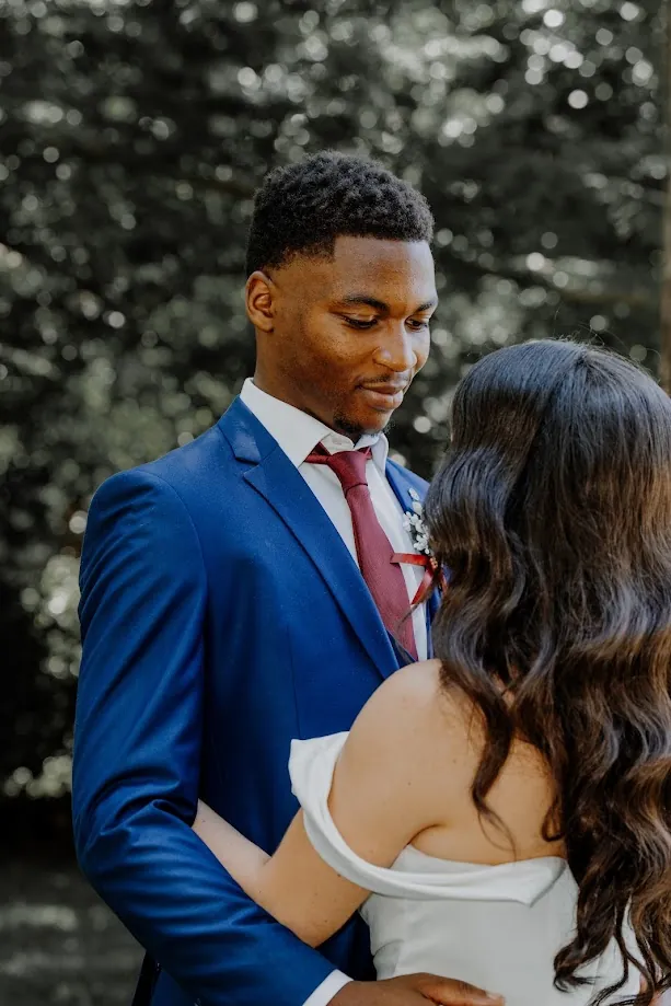 En noir et blanc, la mariée, les yeux fermés, debout dans un hall au sol de mosaïque