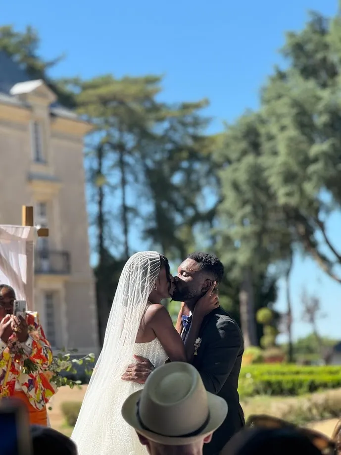 Le baiser des mariés pendant la cérémonie, sous le voile de la mariée, devant le château