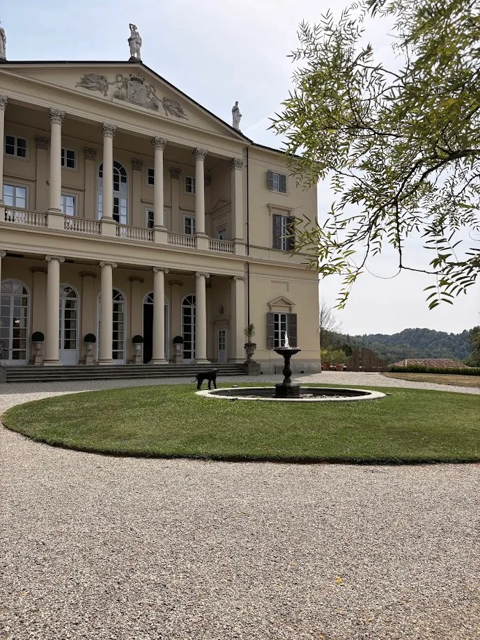 La façade jaune pâle de la villa, ses colonnes et son fronton sculpté, au-dessus d’une pelouse ronde et d’une fontaine