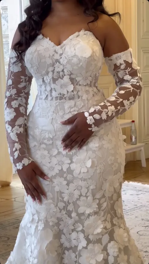 Détail de la robe de la mariée : dentelle fleurie, manches longues transparentes et broderies en relief